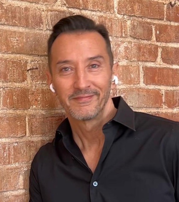 Portrait of author Michael J. Muyot against a brick wall